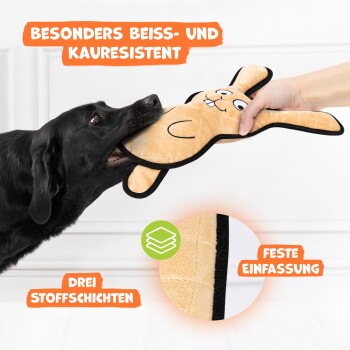 Ein schwarzer Hund beißt verspielt in ein langlebiges Kaninchen-Spielzeug, das seine Kaueigenschaften und Merkmale wie drei Stoffschichten und eine robuste Kante zeigt.