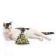 Eine entspannte weiße Katze mit grauen Flecken liegt neben einem bunten dreieckigen Spielzeug mit geometrischen Mustern.
