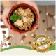 Eine Person hält eine braune Schüssel mit Haustierfutter mit Fleisch, Gemüse und einem Minzblatt, mit einem "Beste Qualität"-Abzeichen und "15 Jahre."