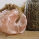 Rosa Himalaya-Salzleckstein mit Tau neben einem Glasbehälter mit braunen Tierpellets auf einer Holzoberfläche.
