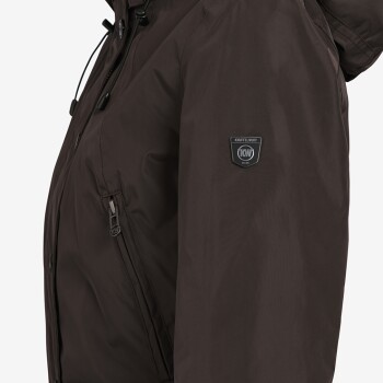 Nahaufnahme einer braunen Jacke mit einer Reißverschlusstasche und einem Logo-Patch am Ärmel, das "KNUFFEL WUFF EST. 1998" liest.