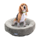 Ein Beagle sitzt bequem in einem runden, plüschigen Hundebett mit grauer und beiger Farbgestaltung, das ein Logo an der Seite hat.