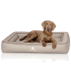 Ein brauner Hund liegt bequem auf einem plüschigen, beigen Hundebett mit erhöhtem Rand, das das Logo 'KNUFFELWUFF' auf der Vorderseite trägt.