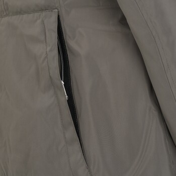 Eine Nahaufnahme einer grauen Jacke, die eine Reißverschlusstasche an der Seite zeigt, wobei die Stofftextur und das Reißverschlussdetail hervorgehoben werden.