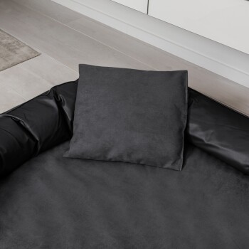 Schwarzes Haustierbett mit einem weichen, plüschigen Schlafbereich und einem abnehmbaren Kissen, mit einem lederähnlichen Äußeren und einem Logopatch.