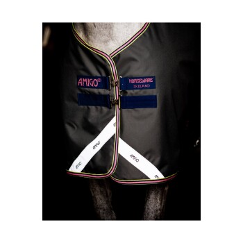 Eine Nahaufnahme eines Pferdes, das eine dunkelgraue Decke mit buntem Rand trägt, mit den Logos "AMIGO" und "HORSEWARE IRELAND."