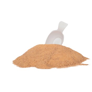 Ein Haufen braunes Nahrungsergänzungsmittel-Pulver mit einer weißen Messschaufel, die teilweise darin vergraben ist, vor einem transparenten Hintergrund.