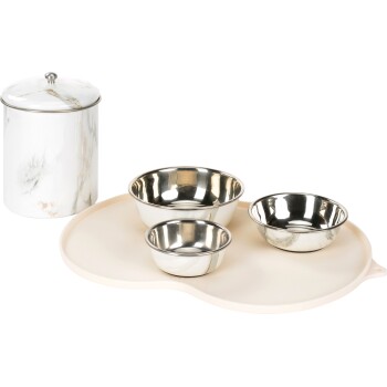 Stylowy zestaw do karmienia zwierząt składający się z trzech stalowych misek o różnych rozmiarach na beżowej tacy, obok pojemnika do przechowywania w marmurowym wzorze.