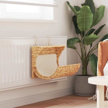 Ein gemütliches, gewebtes Haustierbett, das an einem weißen Heizkörper befestigt ist, mit einem weichen Kissen und einer grünen Pflanze im Hintergrund.