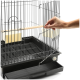Eine Hand öffnet die Tür eines schwarzen Metallvogelkäfigs, der eine Holzstange und zwei gelbe Futterbehälter im Inneren hat.