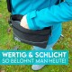 Eine Person in einer blauen Jacke greift in eine schwarze, mit Reißverschluss verschlossene Tasche für Haustierleckerlis gegen Gras. Text: "WERTIG & SCHLICHT SO BELOHNT MAN HEUTE!"