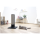 Graue, langhaarige Katze liegt neben einem schwarzen und beigen vertikalen Kratzbaum in einem hellen Wohnzimmer.