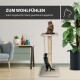 Gemütliches Wohnzimmer mit einem Katzenbaum: eine Katze oben, eine andere klettert. Text: "ZUM WOHLFÜHLEN" und "Hoher Liegekomfort durch gepolsterte Liegeplatte."