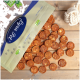 Eine Tüte mit Haustierleckerlis, beschriftet mit 'Fruity Snack', die auf eine Holzoberfläche fällt und runde, braune, fleischige Snacks zeigt.