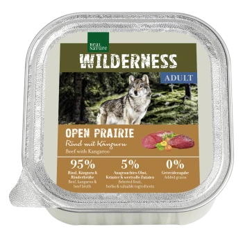 Die Verpackung von Hundefutter zeigt einen Wolf in einem Wald, beschriftet mit "Wilderness Open Prairie", mit "Rindfleisch mit Känguru", 95 % Fleisch, 0 % Getreide.
