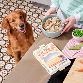 Packung Nutriment Hundefutter mit Rindfleisch, Chicorée, Brokkoli, 81 % Rindfleisch und einem Foto eines braunen Hundes auf rosa Hintergrund.