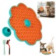 Orangefarbene, blumenförmige Leckmatte für Hunde mit türkisfarbener Umrandung, Saugbasis, Spatel und Bürste; Einsatzbild zeigt Hund in einer Box und zwei Welpen.