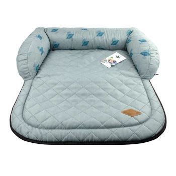 Helle blaue Haustierliege mit gestepptem Design und erhöhten Kanten, mit einem kleinen braunen Logoanhänger und einem angehängten Produktschild.