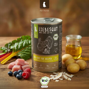 Dose LIEBESGUT Hundefutter mit Aufschrift 'Bio-Pute für Welpen', umgeben von Putenwürfeln, Beeren, Kartoffeln, Mangold und einem Glas Öl.