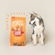 Ein grau-weißer Hund sitzt neben einem orangefarbenen Beutel Edgard Cooper Hundefutter, beschriftet "Saftiges Freilauf-Hühnchen," mit bunten Obstillustrationen.