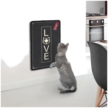 Eine graue Katze steht auf ihren Hinterbeinen und greift nach einem schwarzen Kratzbrett an einer weißen Wand, das das Wort "LIEBE" und ein Katzenicon zeigt.