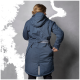 Eine Frau in einer dunkelblauen, kapuzenjacke mit tailliertem Schnitt, die vor einem grauen Hintergrund steht.