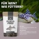 NatureHolic Pleco-Futterbeutel neben einem Zebra-Pleco auf einem Felsen, deutscher Text 'FÜR WEN? WIE FÜTTERN?'.