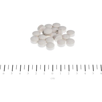 Haufen kleiner weißer runder Tabletten vor weißem Hintergrund über einem Zentimeterlineal mit der Beschriftung "cm" und Markierungen von 0 bis 6.