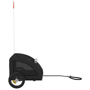 Ein schwarzer Haustieranhänger mit einem Netzfenster, zwei Rädern und einer langen Anhängerkupplung, mit einer roten Flagge oben für Sichtbarkeit.