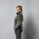 Eine Person in einer grünen Fleecejacke mit einem Reißverschlusskragen und schwarzen Hosen, vor einem grauen Hintergrund stehend.