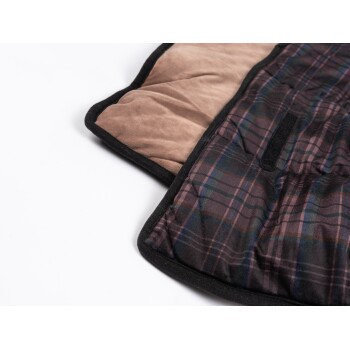 Eine Nahaufnahme einer Haustierdecke mit einem karierten Muster in Dunkelviolett und Grün auf einer Seite und einem weichen braunen Stoff auf der anderen.