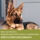 Eine Nahaufnahme eines Deutschen Schäferhundes, der drinnen ruht, mit einem Textüberlagerung auf Deutsch, der sagt: "Reich an Protein, ernährungsphysiologisch ausgewogen, köstlicher Geschmack!"