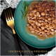 Une assiette turquoise avec de la nourriture pour animaux humide en morceaux, une branche de romarin, une fourchette dorée et une serviette sombre. Texte : 'GESCHMACK OHNE KOMPROMISSE.'