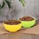 Zwei bunte Schalen, eine gelbe und eine grüne, gefüllt mit Hundefutter, auf einer Juteschicht vor einem strukturierten grauen Hintergrund platziert.
