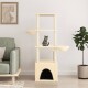 Gemütliches Wohnzimmer mit einem beigen Katzenbaum, einer grauen getigerten Katze auf einer Plattform, einem grünen Sofa und einer Topfpflanze.