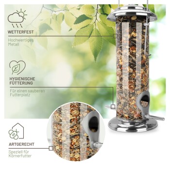 Ein wetterfester Metallvogelhausfütterer, gefüllt mit Samen, mit hygienischer Fütterung und für Getreidefutter konzipiert, vor einem blätterreichen Hintergrund.