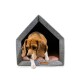 Ein gemütliches, graues Haustierhaus mit einem dreieckigen Dach, ausgestattet mit einem weichen, rosa Kissen innen und einem Hund, der teilweise am Eingang sichtbar ist.