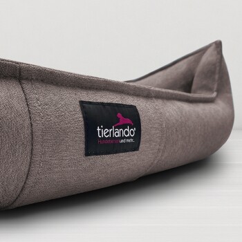 Braunes Stoff-Hundebett mit schwarzem Etikett mit der Aufschrift "tierlando Hundebetten und mehr..." auf heller Oberfläche.