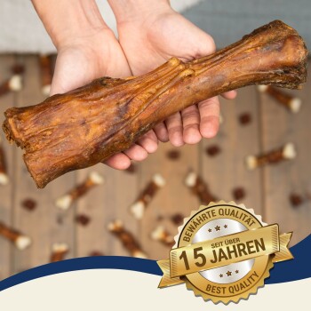 Eine Person hält einen großen Hundeknochen mit kleineren Knochen auf einer Holzoberfläche; ein Abzeichen liest "BESTE QUALITÄT" und "15 JAHREN."