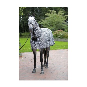 Ein graues Pferd, das eine schwarz-weiße Decke mit Zebramuster trägt, steht auf einem Ziegelweg in einem grünen Garten.