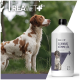 Ein brauner und weißer Hund steht im Freien, schaut nach oben, neben einer Flasche REAVET+ Schwarzkümmelöl, beschriftet mit 'Kaltgepresst aus echtem Schwarzkümmel.'
