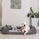 Großer weißer Hund liegt auf einem grauen Haustierbett mit geometrisch gemustertem Kissen in einem modernen Wohnzimmer.