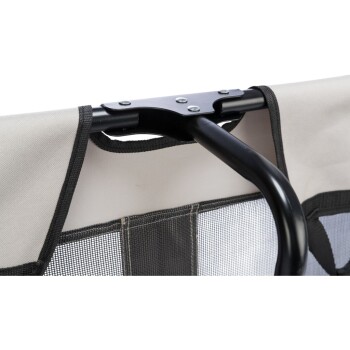 Nahaufnahme des Griffs und des Netzpaneels eines Haustiertransporters, mit einem stabilen schwarzen Metallrahmen und beigem Stoff.