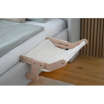 Wandmontierte hölzerne Haustier-Hängematte mit weißem Stofftuch, befestigt an einem grauen Sofa in einem modernen Raum.