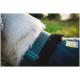 Nahaufnahme des Halses eines Hundes mit einem blauen und schwarzen Geschirr mit einem Logo eines Hundes, vor einem verschwommenen grünen Hintergrund.