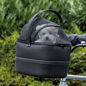 Ein kleiner weißer Hund schaut aus einer schwarzen Tragetasche mit einem Netzoberteil, die an einem Fahrrad befestigt ist, vor einem grünen Hintergrund.