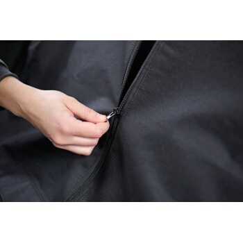 Hand, die einen schwarzen Stoff-Tierträger oder Bezug aufzippt, Nahaufnahme von Reißverschluss und strukturiertem Material.