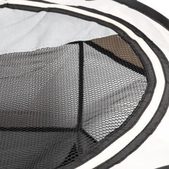 Nahaufnahme einer Haustiertrage mit einem schwarzen Netzpaneel, umgeben von einem hellgrauen Stoff und schwarzem Rand, entworfen für Belüftung.