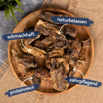 Ein Holzbrett mit Trockenfleischleckerlis für Haustiere, beschriftet mit "lecker", "natürlich", "reich an Protein" und "Zahnpflege."