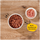 Tierfutter in einer weißen Schüssel, bestehend aus Hackfleisch mit einer Beilage aus rosa Fleischscheiben, beschriftet mit 'Mit 70% Muskelfleisch und feinen Innereien.'